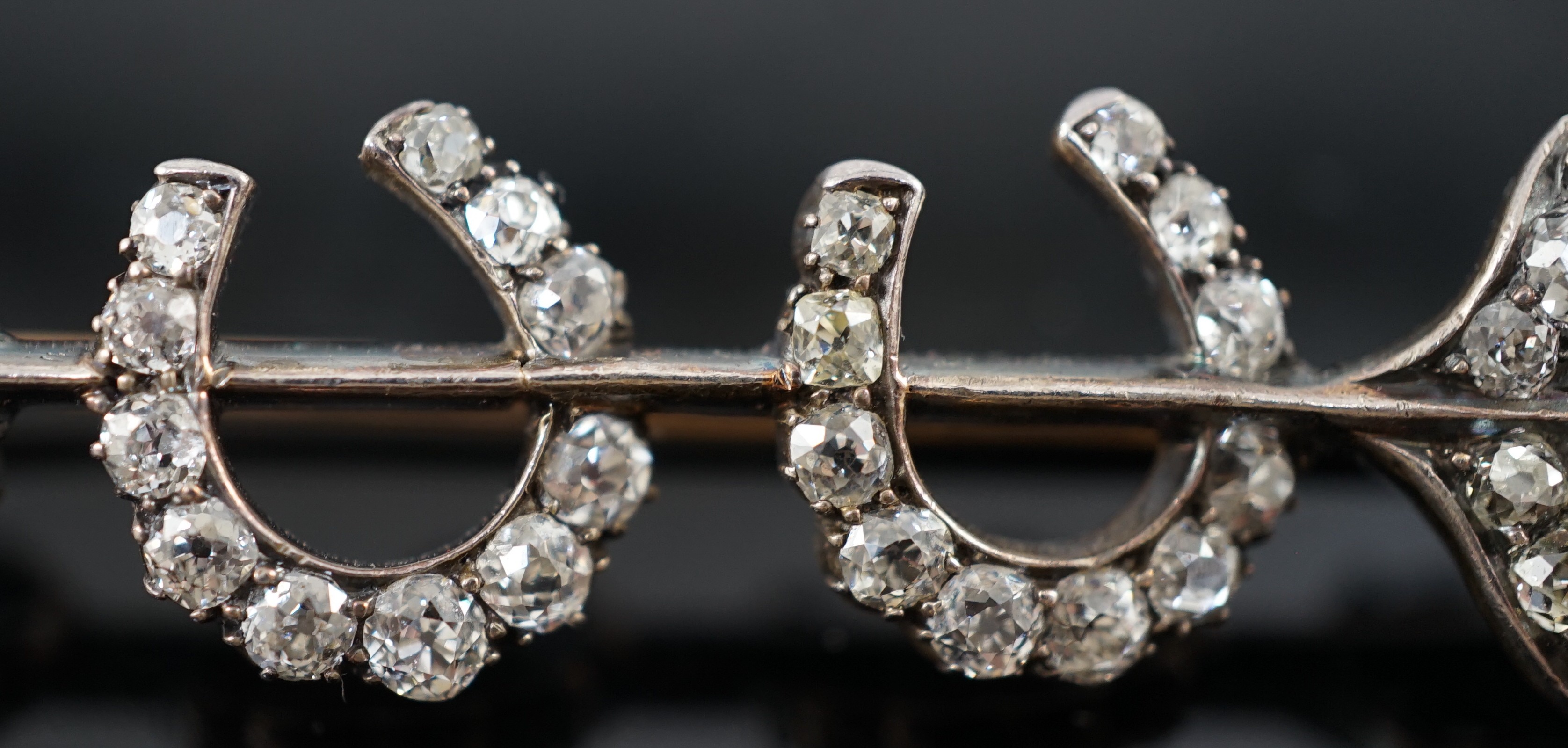 An Edwardian gold, silver and old round cut diamond set gold arrow and triple horseshoe motif set brooch